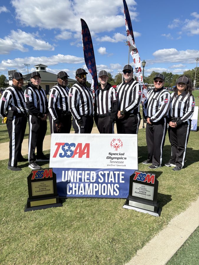 The eight MTFOA officials of the Unified Flag state semifinal and State Championship crews, standing in uniform behind the Unified State Champions banner with the state trophies